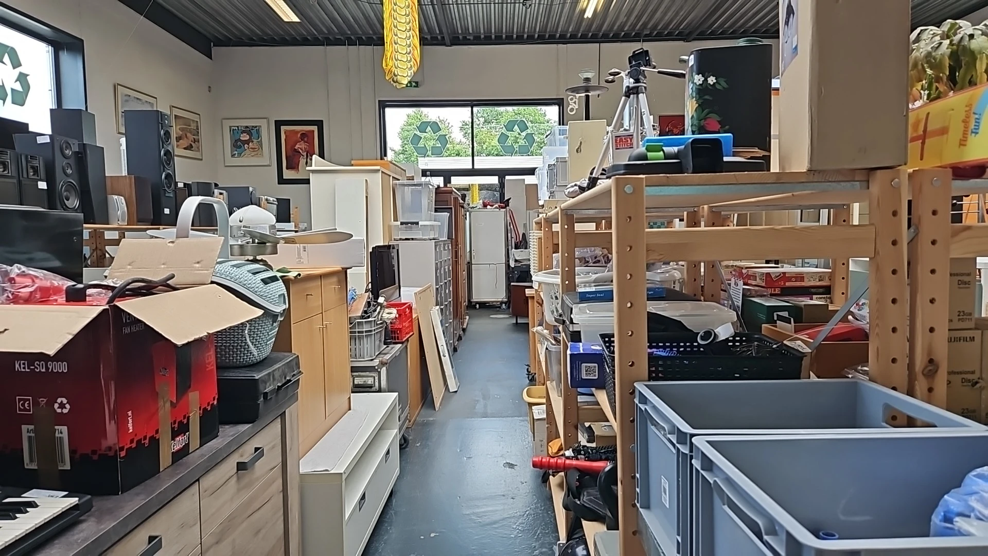 Winkelvloer van kringloopwinkel met houten stellingen, dozen en diverse tweedehands spullen