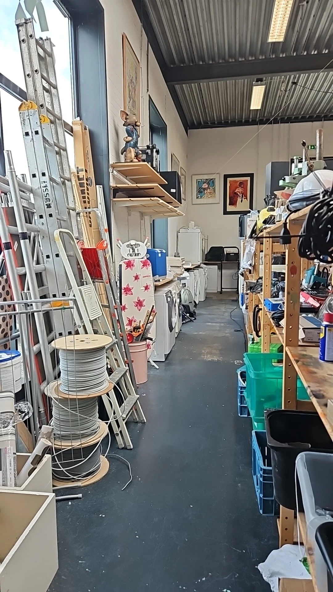 Winkelvloer met stellingen, rekken met kleding en huishoudartikelen, overzicht van het warenaanbod