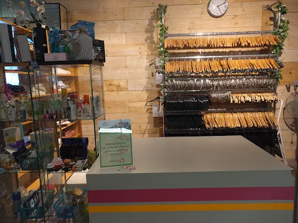 Wanddisplay met uitgestalde riemen in verschillende kleuren en materialen in een kringloopwinkel