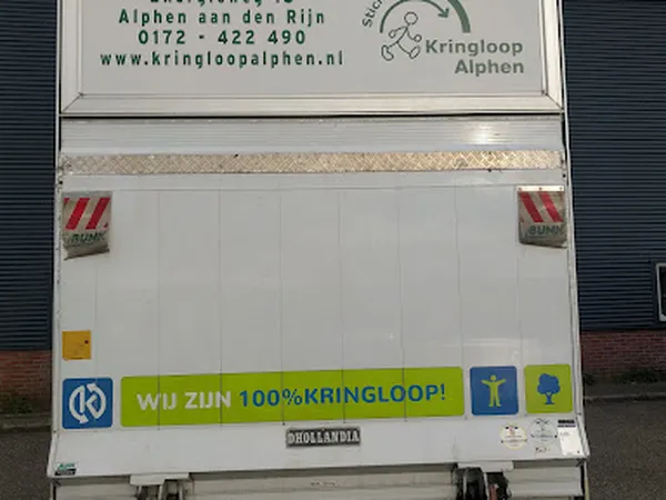 Achterkant van een kringloopwinkel-vrachtwagen met witte deuren en groene banner met tekst 'WIJ ZIJN 100% KRINGLOOP!'
