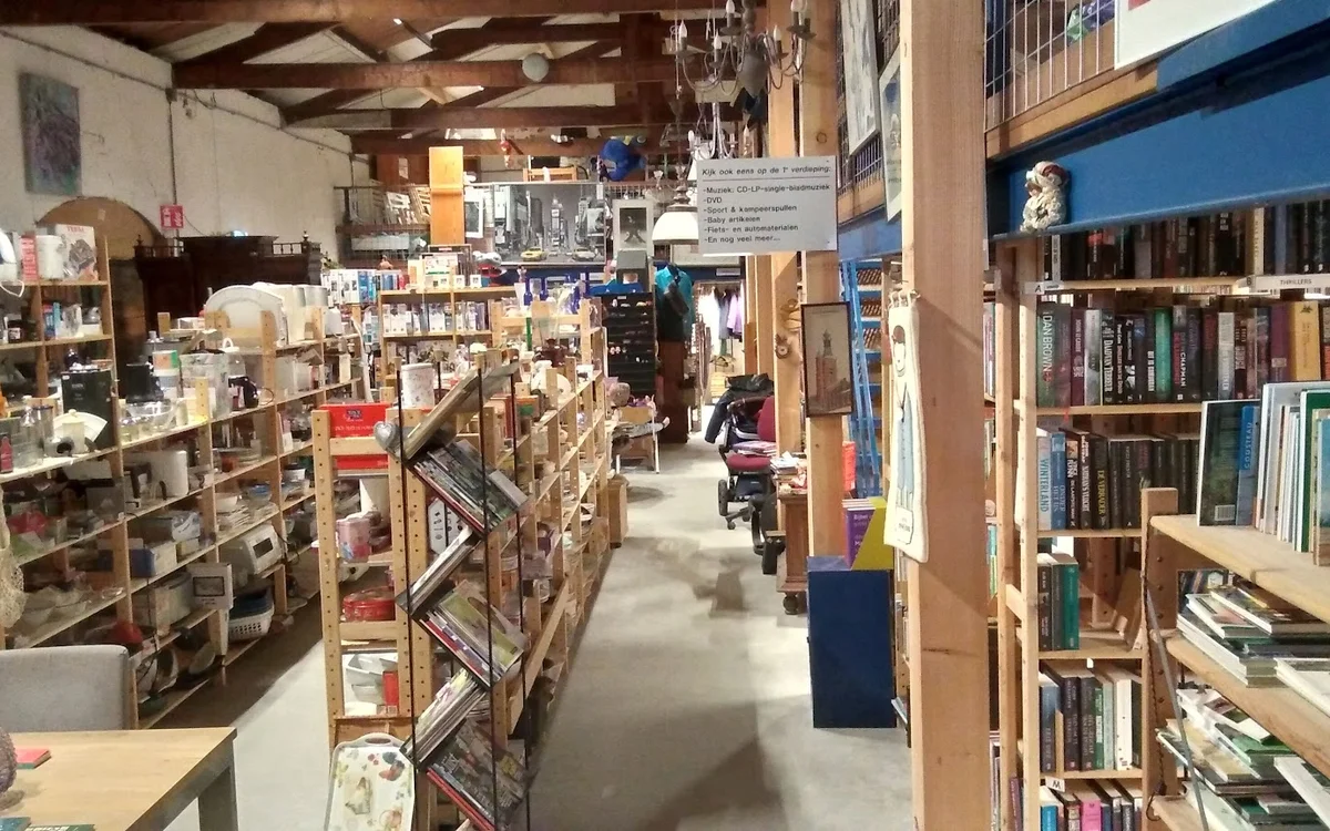 Winkelinterieur met boeken- en mediastellingen langs beide zijden van het gangpad
