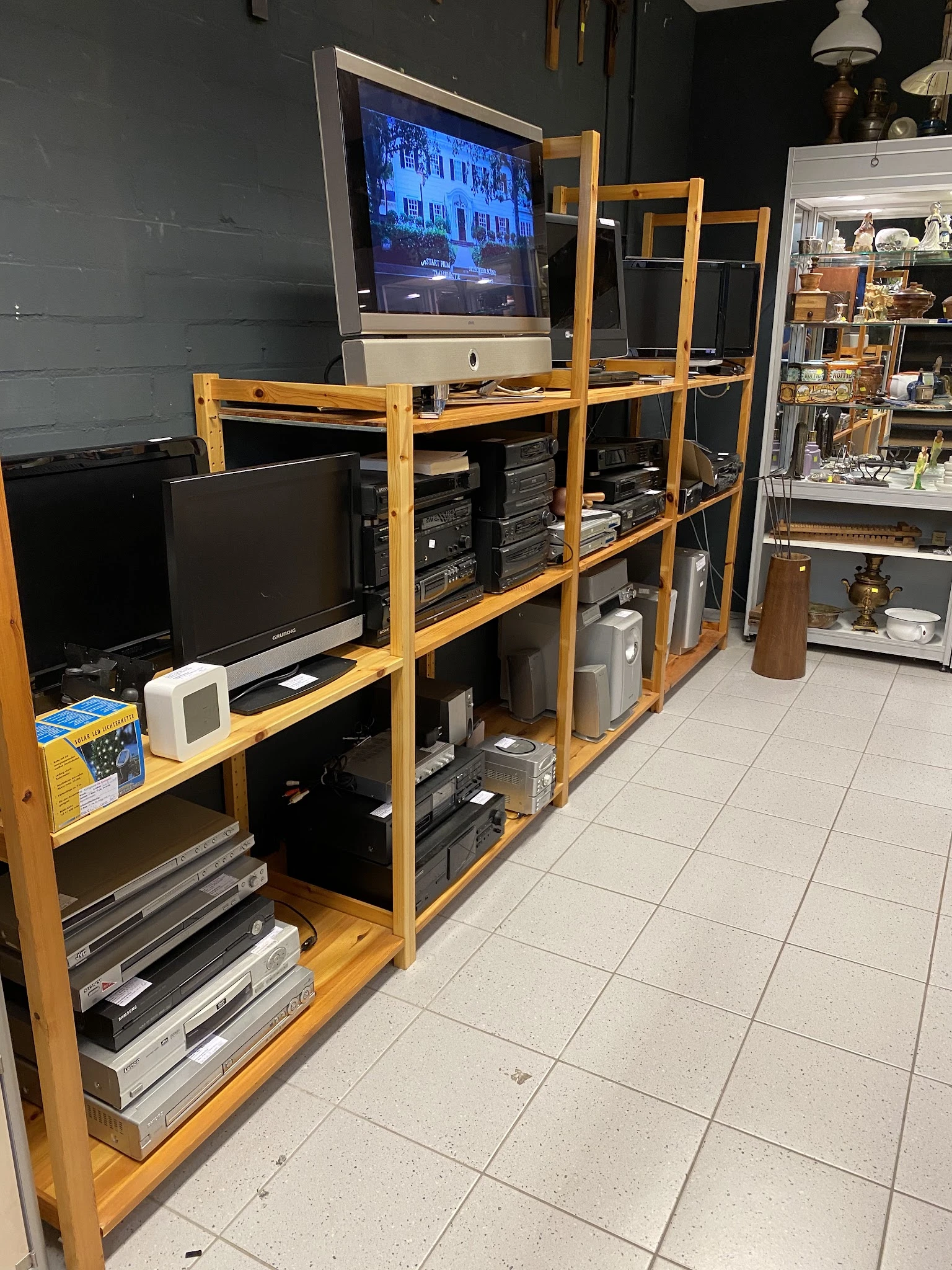 Houten stellingen met elektronische apparatuur zoals monitoren, computers en printers in een kringloopwinkel