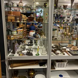 Glazen vitrinekasten met uitgestalde tweedehands huishoudspullen, servies, beeldjes en decoratieve items