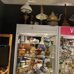 Vitrinekast met diverse huishoudelijke artikelen: koperen en metalen ketelwerk, servies en decoratieve objecten