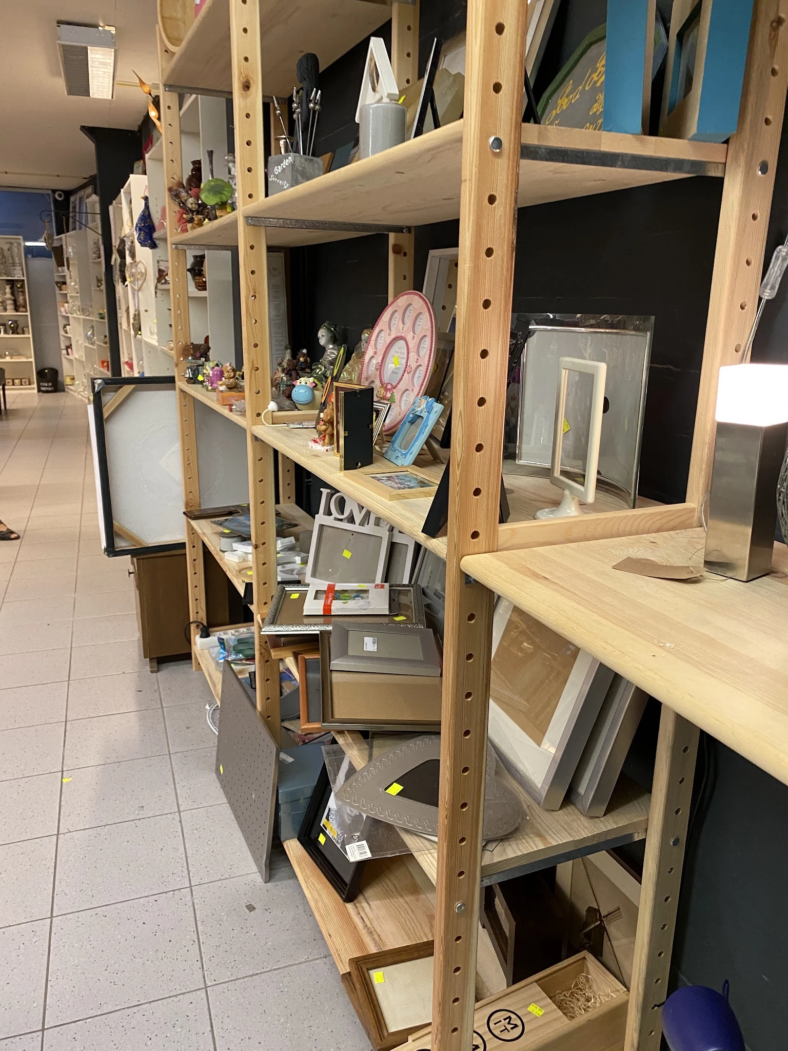 Houten stellingen met diverse tweedehands artikelen zoals decoratie, elektronische apparaten en huishoudartikelen