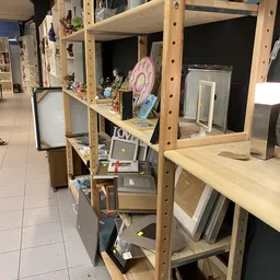 Houten stellingen met diverse tweedehands artikelen zoals decoratie, elektronische apparaten en huishoudartikelen