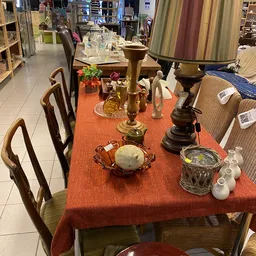 Tafel met oranje loper gedekt met diverse decoratieve voorwerpen: kandelaars, bloemen, beeldjes en aardewerk