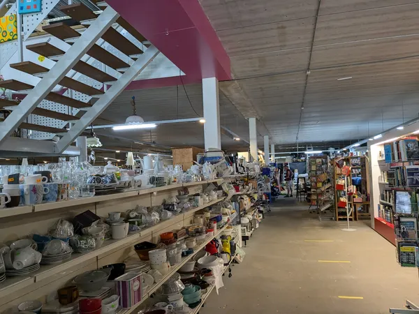 Winkelinterieur met houten stellingen vol huishoudartikelen en decoratieobjecten, gele lijnmarkeringen op vloer