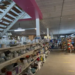 Winkelinterieur met houten stellingen vol huishoudartikelen en decoratieobjecten, gele lijnmarkeringen op vloer