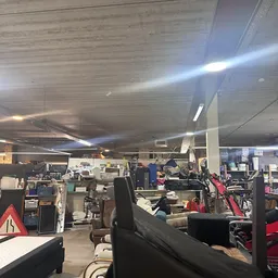 Winkelvloer met verschillende rekken, stellingen en spullen; matig verlicht interieur van een kringloopwinkel