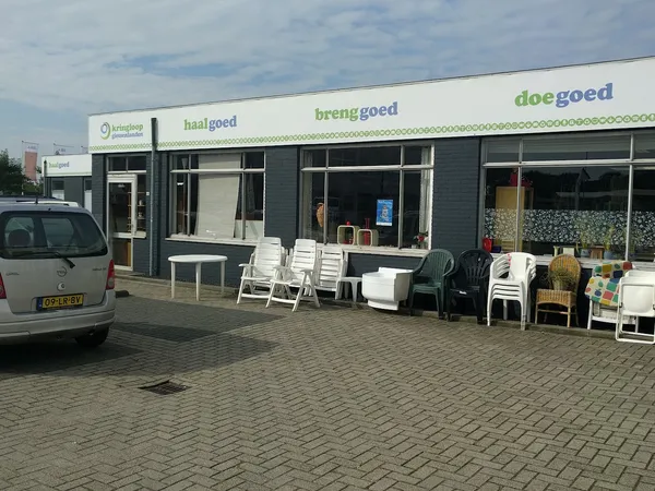 Gevel van kringloopwinkel met uitstallingen stoelen en meubels op het plein ervoor