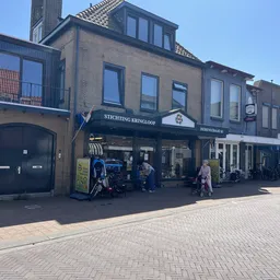 Voorgevel van kringloopwinkel met blauwe luifel, etalages en ingang aan Herenstraat