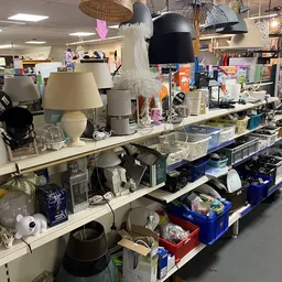 Tafellampen, huishoudartikelen en diverse spullen op stellingen in de kringloopwinkel