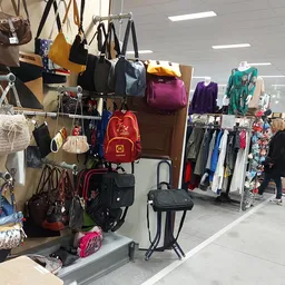 Uitgestalde tassen, rugzakken en kledingrekken in een kringloopwinkel