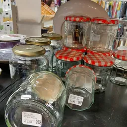 Glazen potten en bokalen met metalen en rood-witte geruite deksels op een zwarte tafel