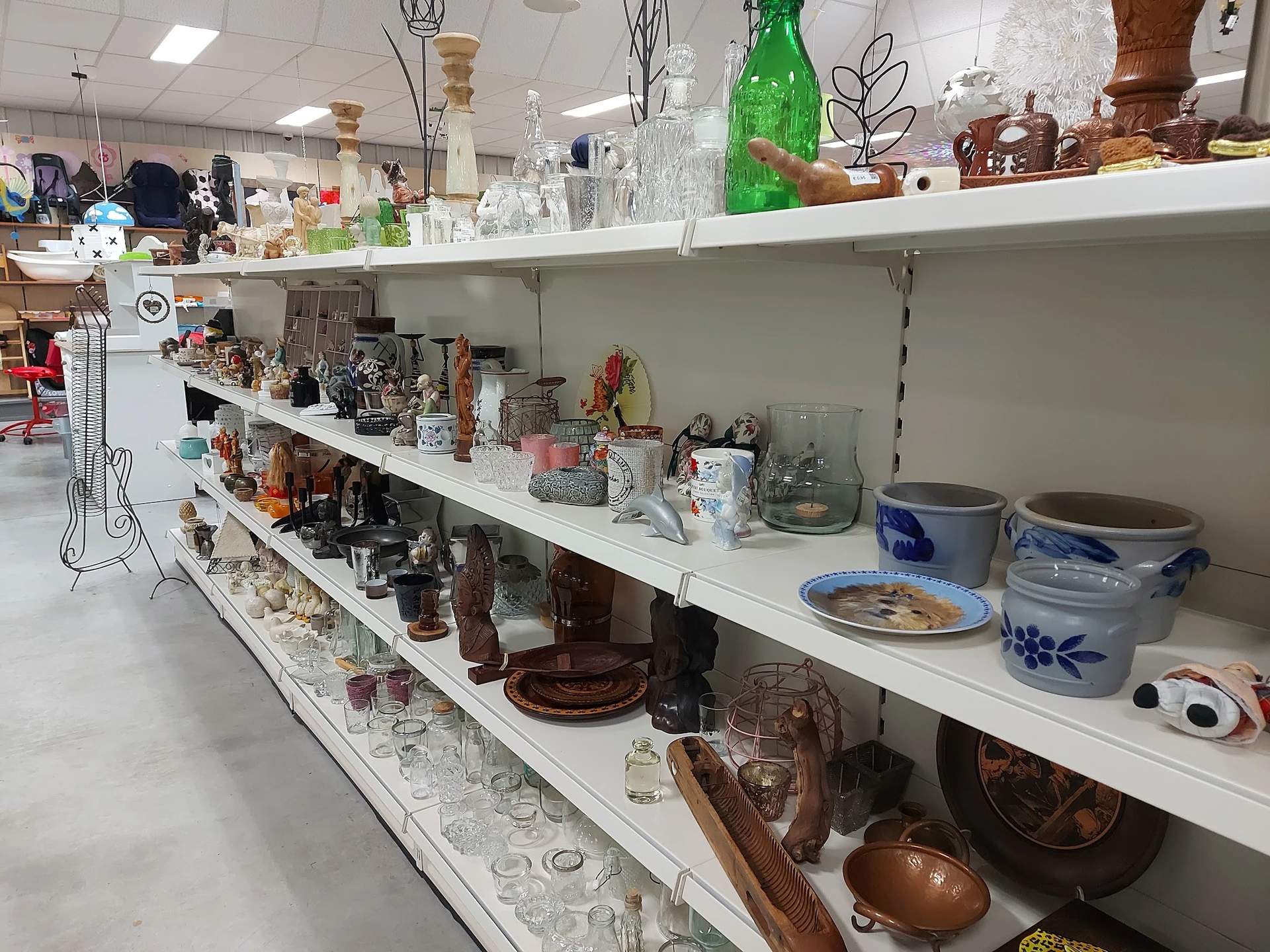 Witte stellingen met diverse huishoudelijke artikelen, glazen, vazen, servies en decoratieve items