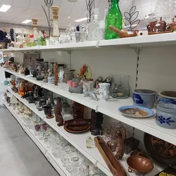 Witte stellingen met diverse huishoudelijke artikelen, glazen, vazen, servies en decoratieve items