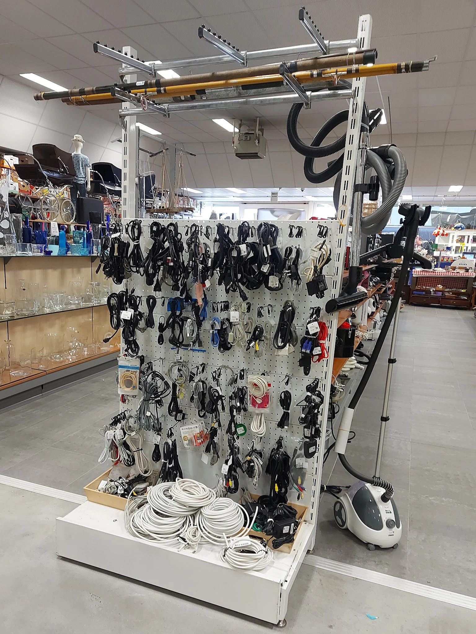Uitgestalde elektrische kabels en snoeren op een wit rek in de kringloopwinkel