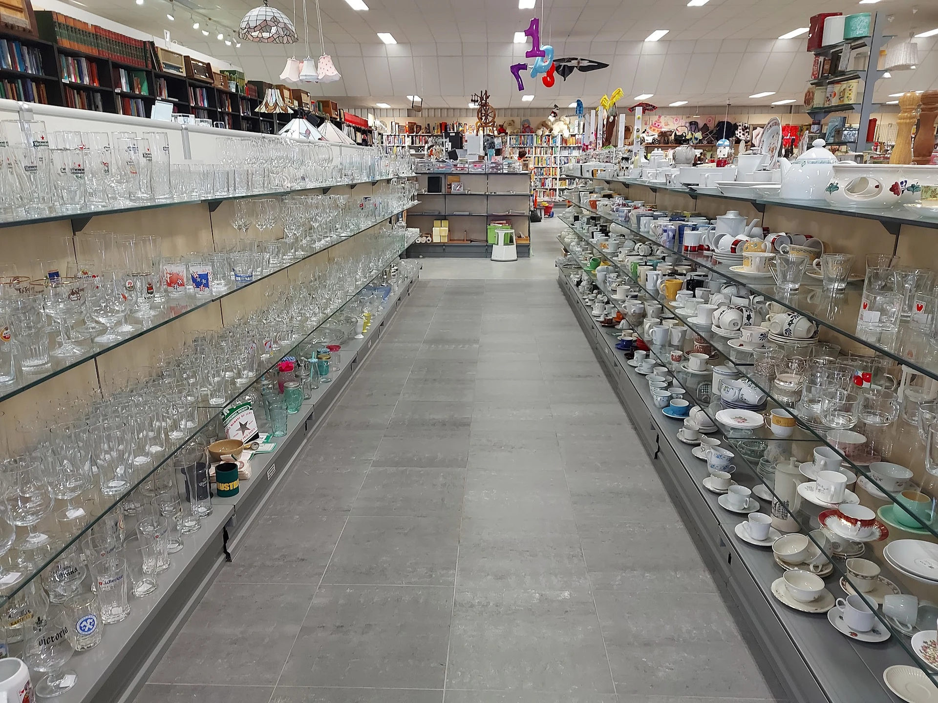 Lange gang met glazen vitrines vol servies, glazen en decoratieve artikelen aan beide zijden