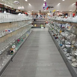Lange gang met glazen vitrines vol servies, glazen en decoratieve artikelen aan beide zijden