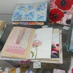 Uitgestalde notitieboeken, schetsblokken en decoratieve items met bloemmotieven op tafel