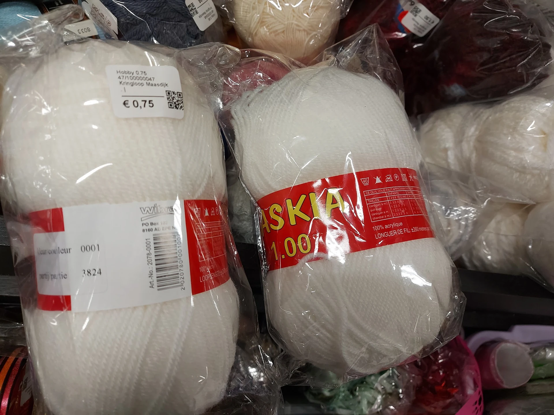 Wollen bollen in verschillende kleuren, verpakt in plastic met prijskaartjes en merklabels