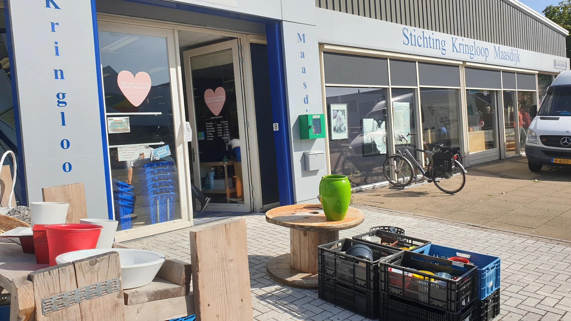 Winkelgevel met blauwe deurpui, hartje op raam, en terras met groene bloempot vooraan