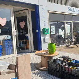 Winkelgevel met blauwe deurpui, hartje op raam, en terras met groene bloempot vooraan