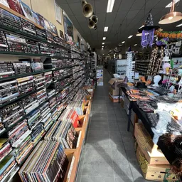 Binnenaanzicht van kringloopwinkel met rekken vol dvd's en blu-rays aan linkerkant, toonbank met merchandise aan rechterkant