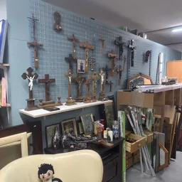 Uitgestalde religieuze artikelen: verschillende houten en bronzen kruisen aan de muur en beeldjes op een toonbank in de kring