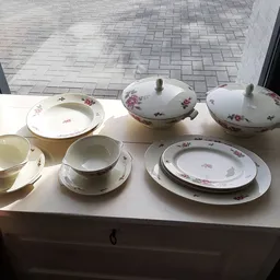 Servies met bloemmotief: borden, schalen, kopjes en schotels op wit dressoir