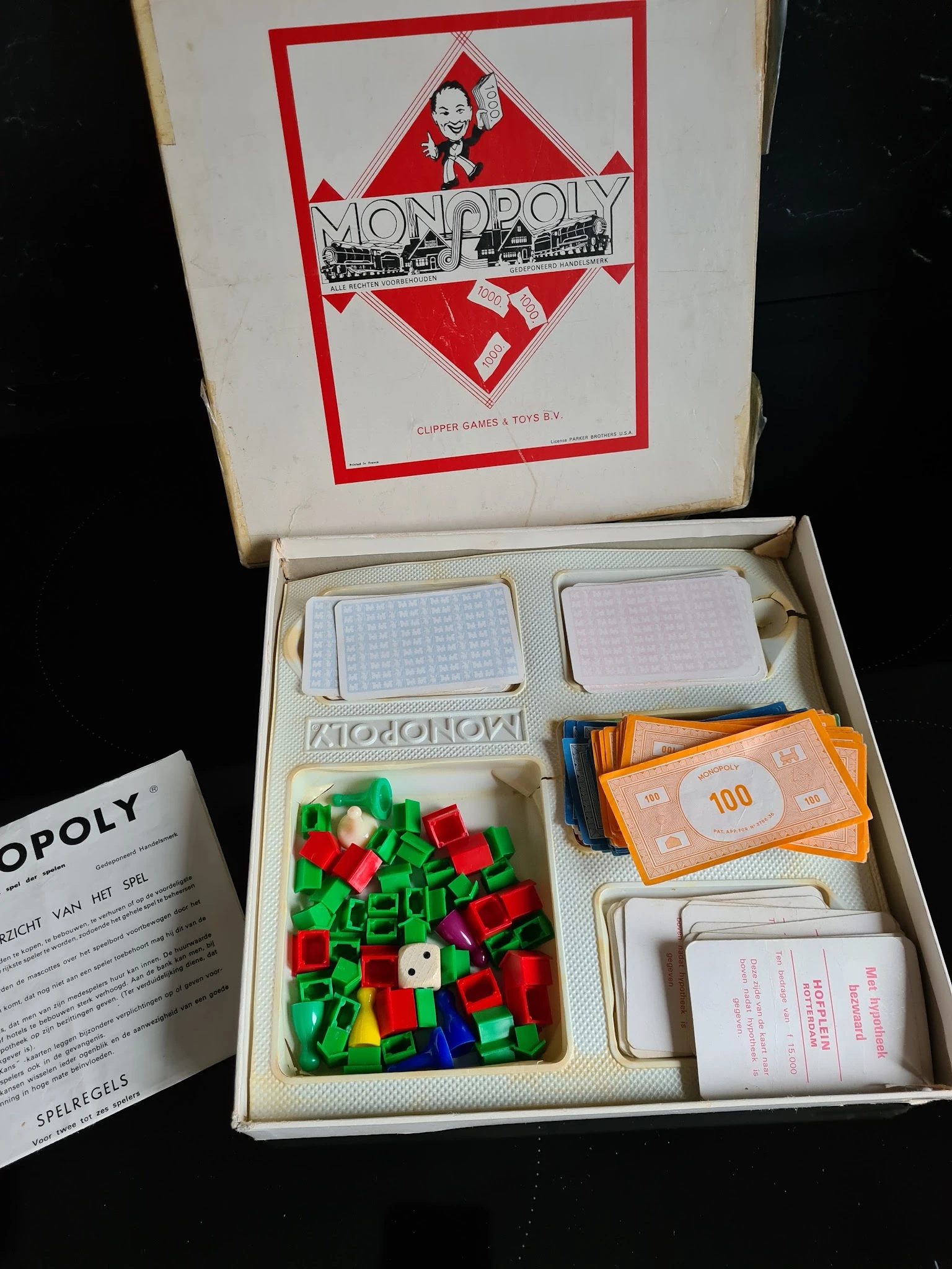 Vintage Monopoly-spel in open doos met speelstukken, kaarten en geld zichtbaar