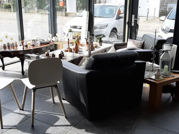 Winkelvloer met zwarte fauteuil, houten tafels en grote ramen met uitzicht op straat