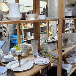 Uitgestalde serviesgoed, potten en huishoudelijke artikelen op houten stellingen in de winkel