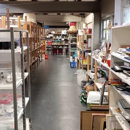 Winkelgang in kringloopwinkel met stellingen vol spullen aan beide zijden