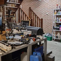 Werkbank met gereedschap en onderdelen in een kringloopwinkel, met stellingen en bakken op de achtergrond