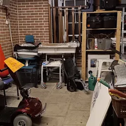 Rommelachtig opslagruimte met diverse spullen, meubels, dozen en huishoudelijke artikelen