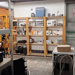 Houten stellingen gevuld met huishoudelijke apparaten en elektronica in de kringloopwinkel