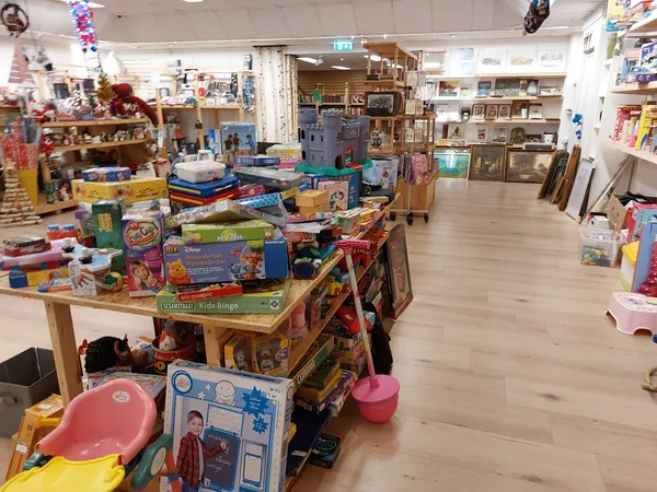 Winkelvloer van kringloopwinkel met speelgoed, spellen en kinderspullen op tafels en stellingen