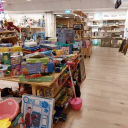 Winkelvloer van kringloopwinkel met speelgoed, spellen en kinderspullen op tafels en stellingen