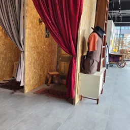Winkelinterieur met kledingrekken, paskamers met gekleurde gordijnen en een hoedenmanchet op display.