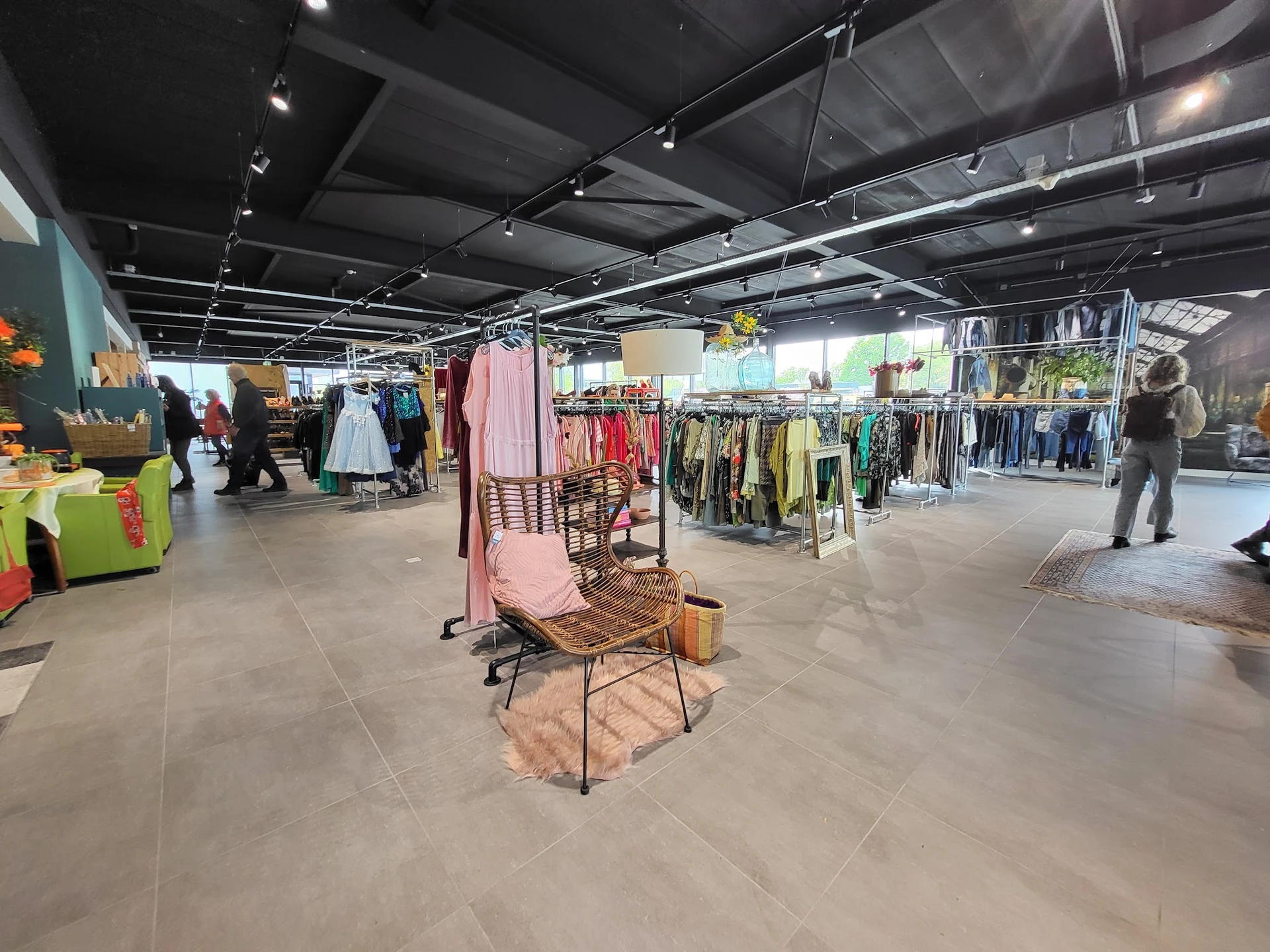 Winkelinterieur met kledingrekken, display-pop-up met roze stoel en verschillende afdeling voor tweedehands kleding