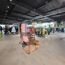 Winkelinterieur met kledingrekken, display-pop-up met roze stoel en verschillende afdeling voor tweedehands kleding