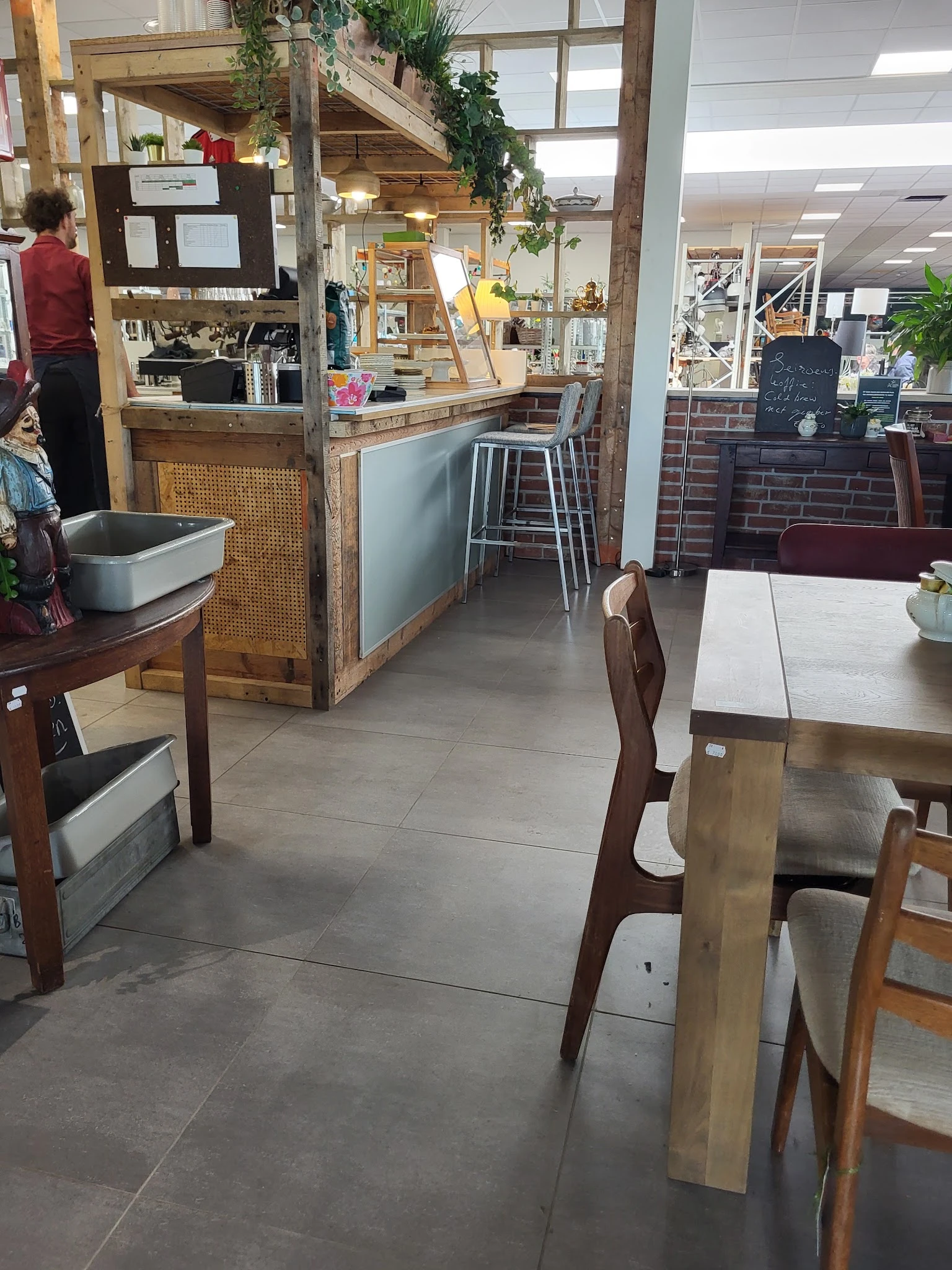 Winkelinterieur met houten tafels, stoelen, toonbank en stellingen met spullen