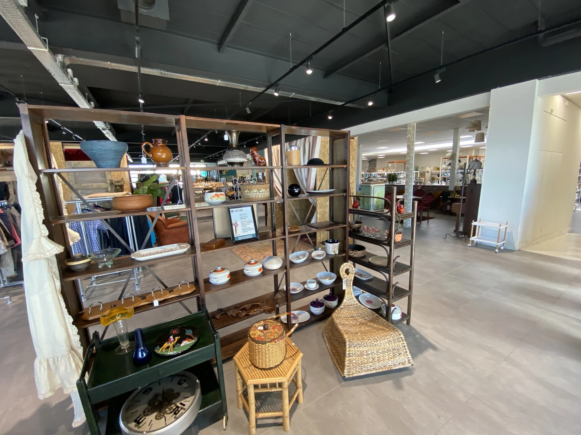 Uitgestalde huishoudartikelen, servies en decoratie op houten stellingen en tafels in de kringloopwinkel