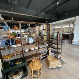 Uitgestalde huishoudartikelen, servies en decoratie op houten stellingen en tafels in de kringloopwinkel