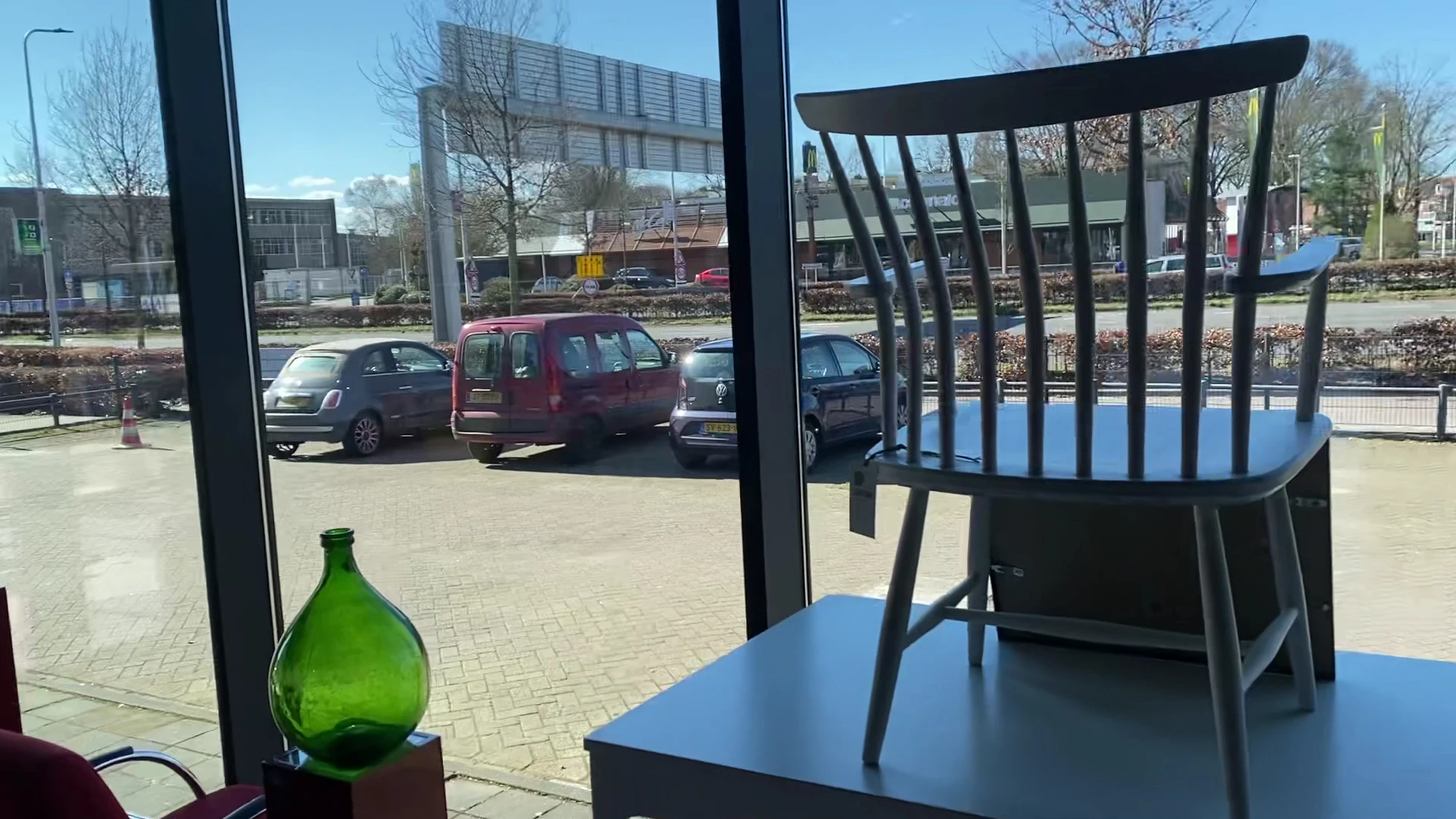 Zicht vanuit een lunchroom op een parkeerterrein met auto's en gebouwen