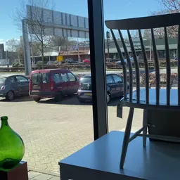 Zicht vanuit een lunchroom op een parkeerterrein met auto's en gebouwen