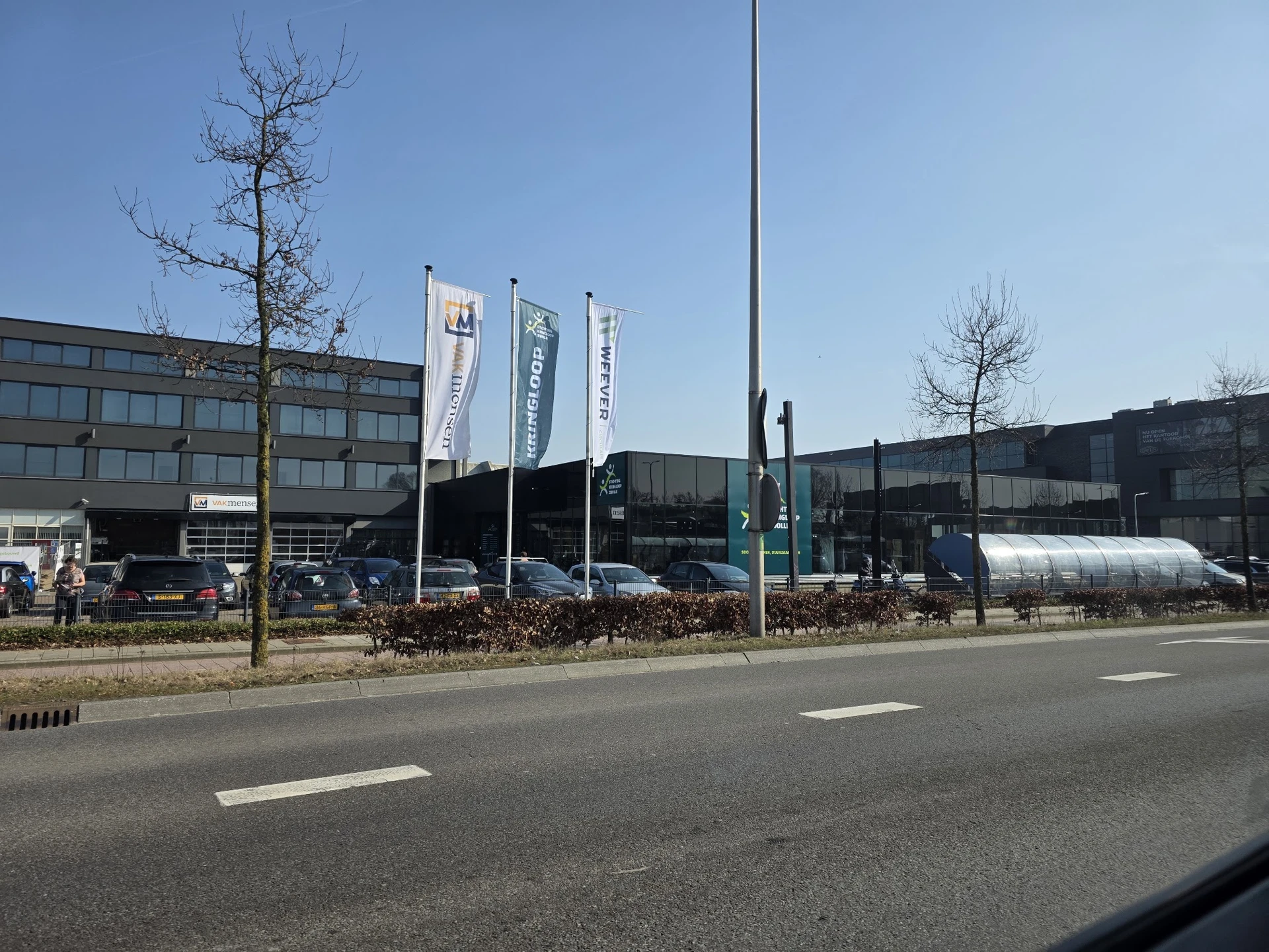 Exterieur van een kringloopwinkel met banners aan de voorgevel, vanaf de straat gezien