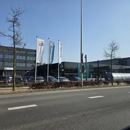 Exterieur van een kringloopwinkel met banners aan de voorgevel, vanaf de straat gezien